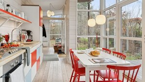Eine moderne Küche mit weißen Schränken, einer Holzauskleidung und roten Stühlen um einen weißen Tisch.