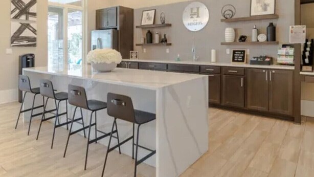 Een moderne keuken met een centraal eiland, barstoelen en een kroonluchter.