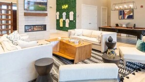 Een moderne hotelentree met een open haard, een pooltafel en een groene wand met sporttenues.