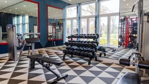 Een fitnessruimte met een geruit vloertje, gewichtrekken en trainingsapparatuur.
