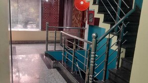A staircase with metal railings and a red circular object on the wall. - Hotel Mukesh Palace (Prayagraj)