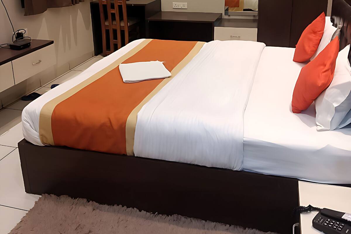 Une chambre d’hôtel comprenant un lit, un bureau, une chaise, une armoire et un miroir.
