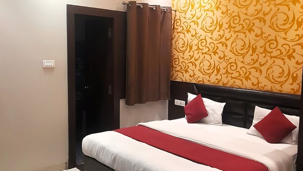 A modern bedroom with a large bed, a ceiling fan, and a patterned wallpaper. - Hotel Mukesh Palace (Prayagraj)