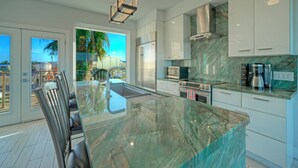 A modern kitchen with a large island, stainless steel appliances, and a view of the outdoors. - Modern Coastal Home w/ Balcony, Firepit & Prime Port A Location | Casa Blanca (Port Aransas)