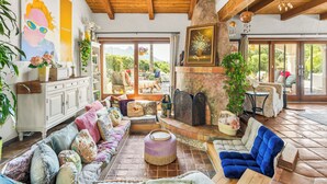 Un salón amplio con chimenea, asientos cómodos y grandes ventanas con vistas al exterior.
