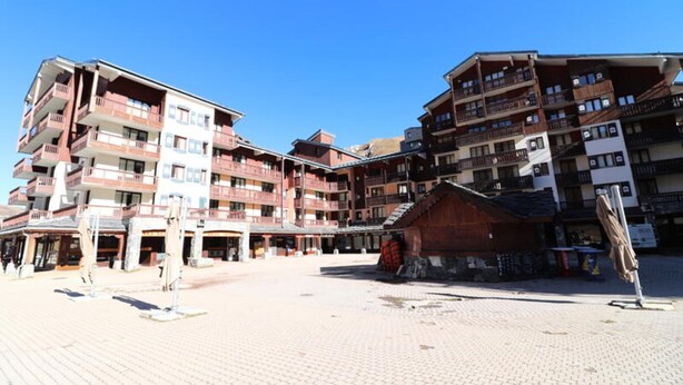 A multi-story hotel with balconies, a central courtyard, and a small wooden structure. - Studio Close to the Slopes Balcony (Tignes)