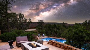 A backyard with a fire pit, outdoor seating, a swimming pool, and a starry night sky. - Luxe Red Rock Views, Heated Pool & Spa, Hot tub (Sedona)