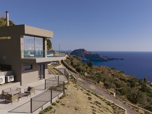 Ein modernes Haus mit Balkon und Blick auf eine Küstenlandschaft.