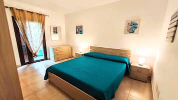 Ein Schlafzimmer mit Bett, Holzkommode, Nachttischen und Wandbildern.