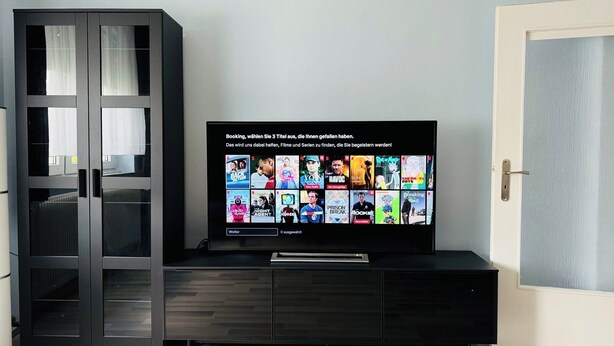 Een moderne entertainmentkast met een flatscreen televisie waarop een keuze aan films en tv-programma's wordt getoond.