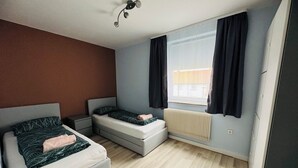 Een moderne slaapkamer met een bed, een kleine zithoek, een verwarming en een raam met gordijnen.