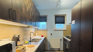 Een moderne keuken met donkere kastjes, een RVS spoelbak en een inbouwoven.