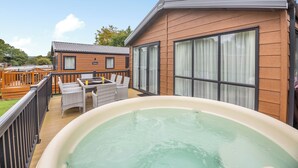 Un bain à remous sur une terrasse, des bâtiments en bois et un ciel dégagé.