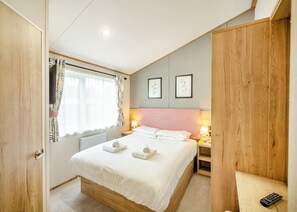 A bedroom with a bed, bedside lamps, a window with curtains, and framed artwork on the wall. - 4 bedroom accommodation in Bala, (Bala,)