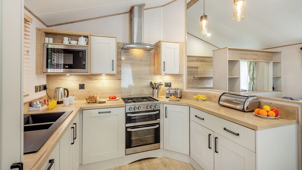 Une cuisine moderne avec des armoires blanches, une cuisinière en acier inoxydable et un plan de travail en bois.