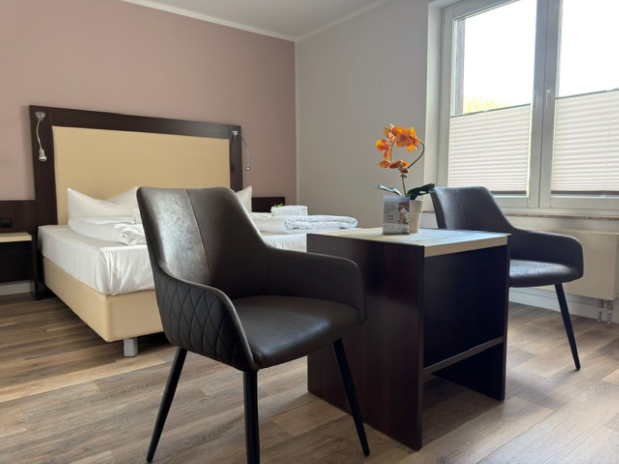 Ein Hotelzimmer mit einem Bett, zwei Stühlen, einem Schreibtisch und einem Fenster.