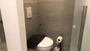 A small, modern bathroom with a toilet, a towel, and a toilet paper holder. - Stylish Apt Near Wiener Stadthalle (Vienna)