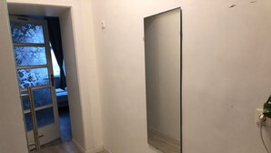 A hallway with a wooden floor, a door with frosted glass panels, and a wall-mounted light fixture. - Stylish Apt Near Wiener Stadthalle (Vienna)