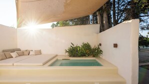 Een zwembadgedeelte met een zonnig hoekje, een comfortabele zithoek en een kleine tuin.