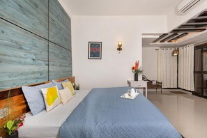 Un dormitorio moderno con una cama grande, un muro decorativo de madera, una mesita de noche con un florero y vistas al exterior a través de un ventanal.
