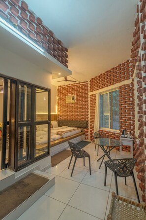 Ein Zimmer mit Backsteinwand, einem Bett, einem Tisch mit Stühlen und einem Fenster.