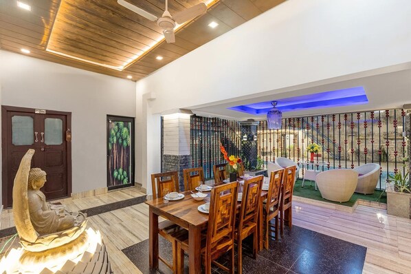 Un espace repas avec une table et des chaises en bois, une statue de Bouddha et un mur décoratif.