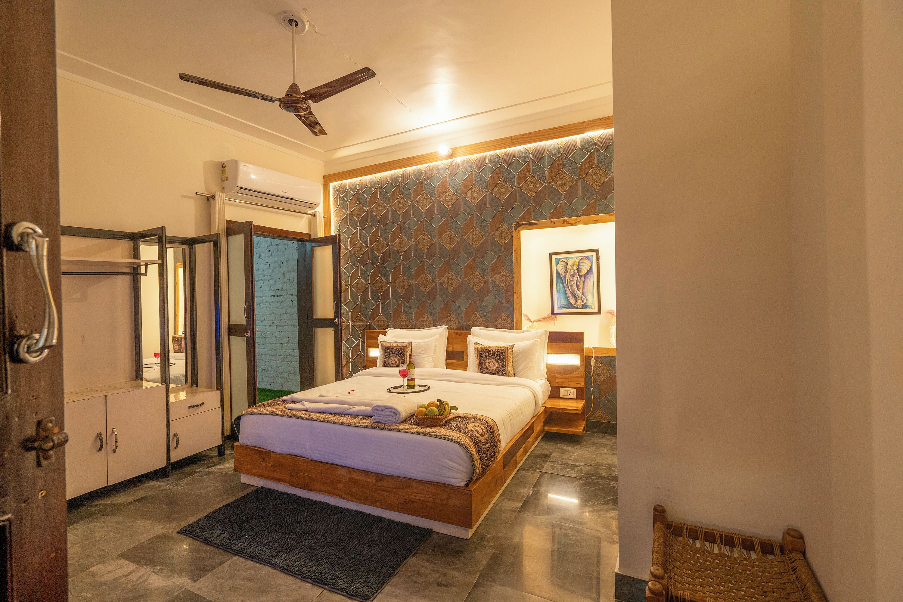 A hotel room with a bed, bedside table, lamp, and a decorative wall.