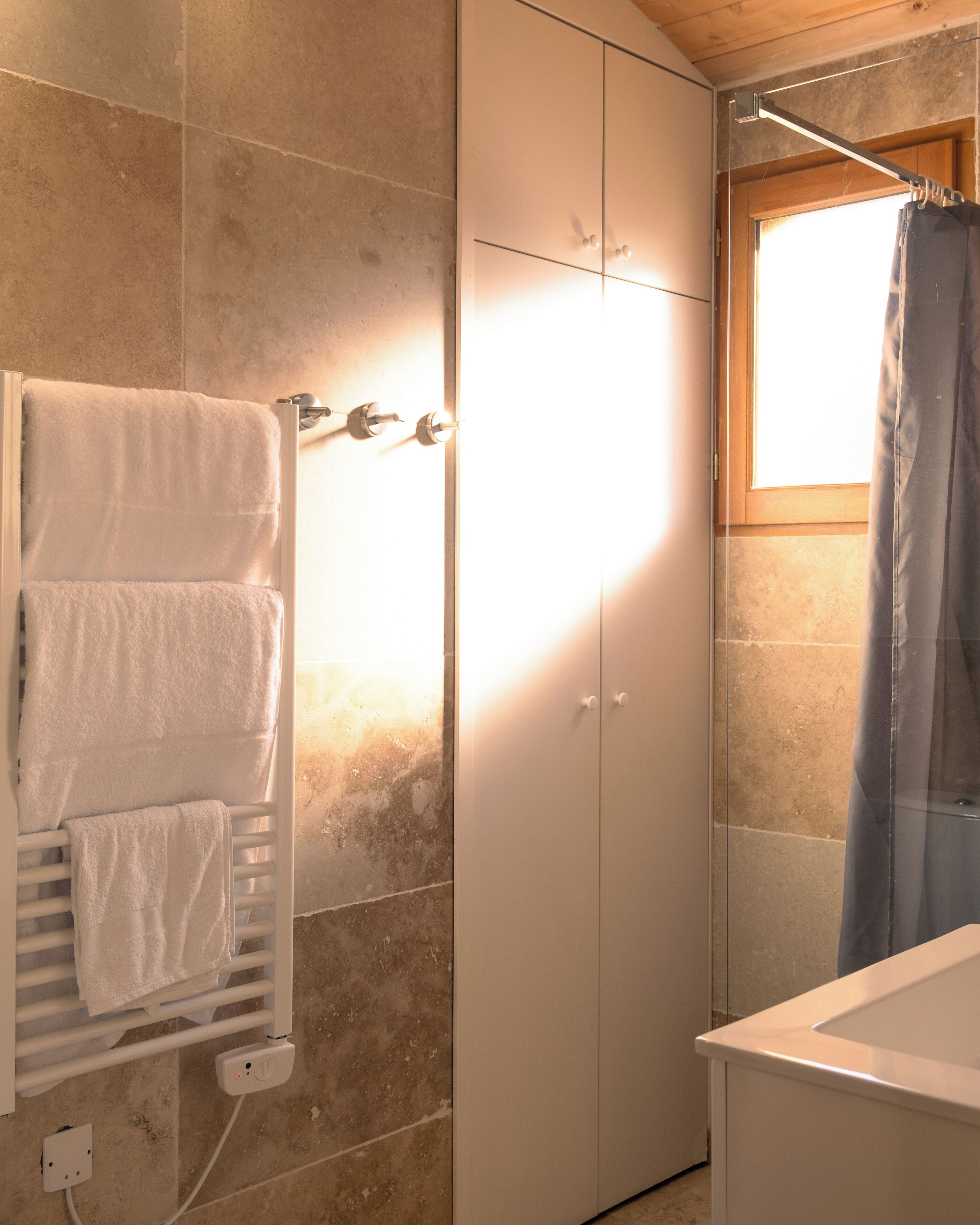 Une salle de bain avec un rideau de douche, un porte-serviettes avec des serviettes et une fenêtre.