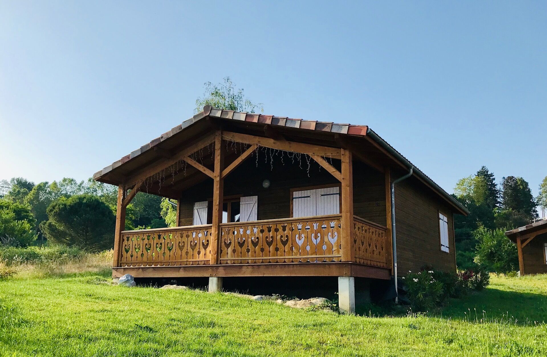 Una cabaña de madera con balcón, rodeada de vegetación.