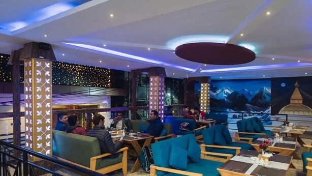 A modern lounge area with wooden furniture, a mural of mountains, and decorative lighting. - Luna Hotel And Lounge (Kathmandu)