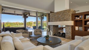 Un amplio salón con un sofá modular grande, una mesa de centro redonda y una chimenea de piedra.