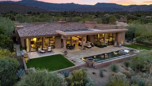 Una casa moderna con patio, mobiliario exterior y piscina.