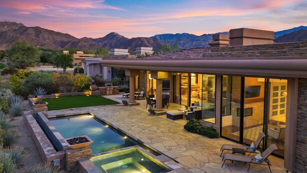 Una casa moderna con piscina, mobiliario exterior y vistas a la montaña.