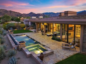 Una casa moderna con piscina, mobiliario exterior y vistas a la montaña.