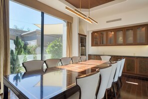 Un comedor moderno con una mesa grande, sillas y una cocina con armarios de madera.