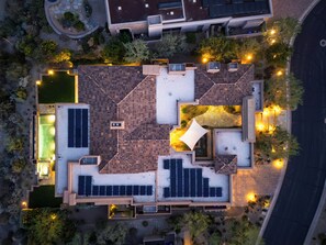 Vista aérea de una propiedad residencial con terraza en la azotea, paneles solares y piscina.