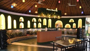 A restaurant with a thatched roof, green walls, and a bar area. - PRAKARAM RESORT AND CAFE (Ramnagar)