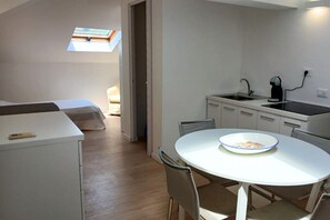 A compact room with a bed, a small kitchenette, a round dining table with a bowl, and a skylight. -  CV017 - Milano Marittima, elegant attic with air conditioning (Milano Marittima)