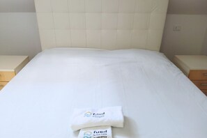 A neatly made bed with a white headboard and a towel with the logo 'fued' on it. -  CV017 - Milano Marittima, elegant attic with air conditioning (Milano Marittima)