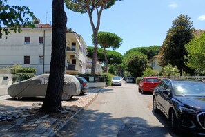 Un carrer residencial amb cotxes aparcats, una vorera arbrada i edificis d'alguns pisos.