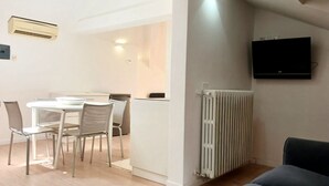 Un salon moderne comprenant un coin repas, un radiateur et un téléviseur fixé au mur.