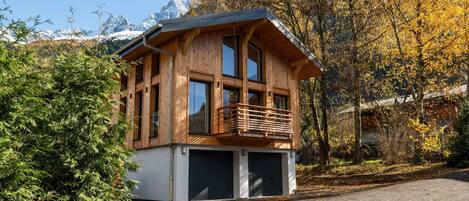 Una cabaña de madera con balcón, ventanas amplias y garaje.