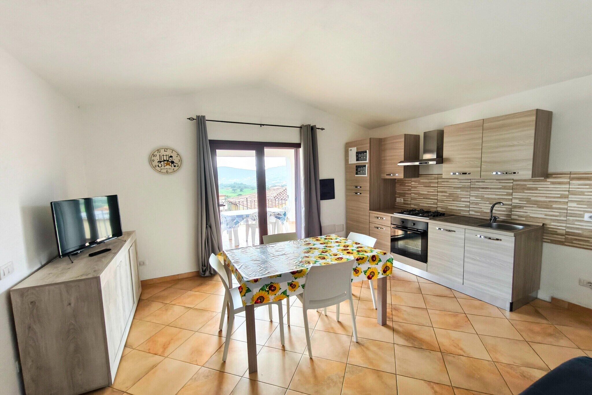 Cocina compacta con mesa de comedor, un televisor en un mueble y vistas a través de la ventana.