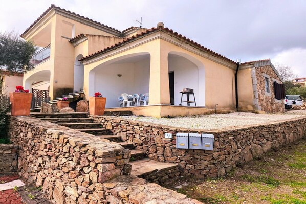 Um edifício de dois andares com um muro de arrimo de pedra e uma varanda.