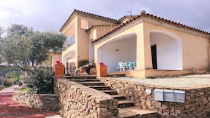 A two-story building with a stone staircase leading to a covered porch. - Apartment with a sea-view terrace (Budoni)