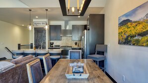 Una cocina moderna con una isla central, asientos tipo bar y una mesa de comedor con una bandeja.