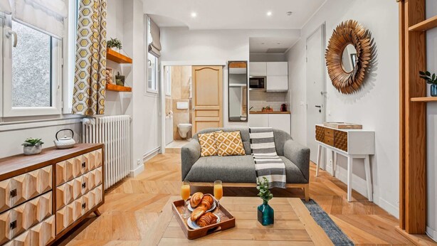 A modern living room with a sofa, a coffee table with pastries, and a breakfast tray. - Elegant Studio in 16th - Eiffel Tower & Trocadero (Paris)