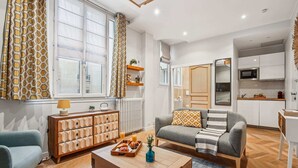 A modern living room with a sofa, coffee table, and a wooden cabinet. - Elegant Studio in 16th - Eiffel Tower & Trocadero (Paris)