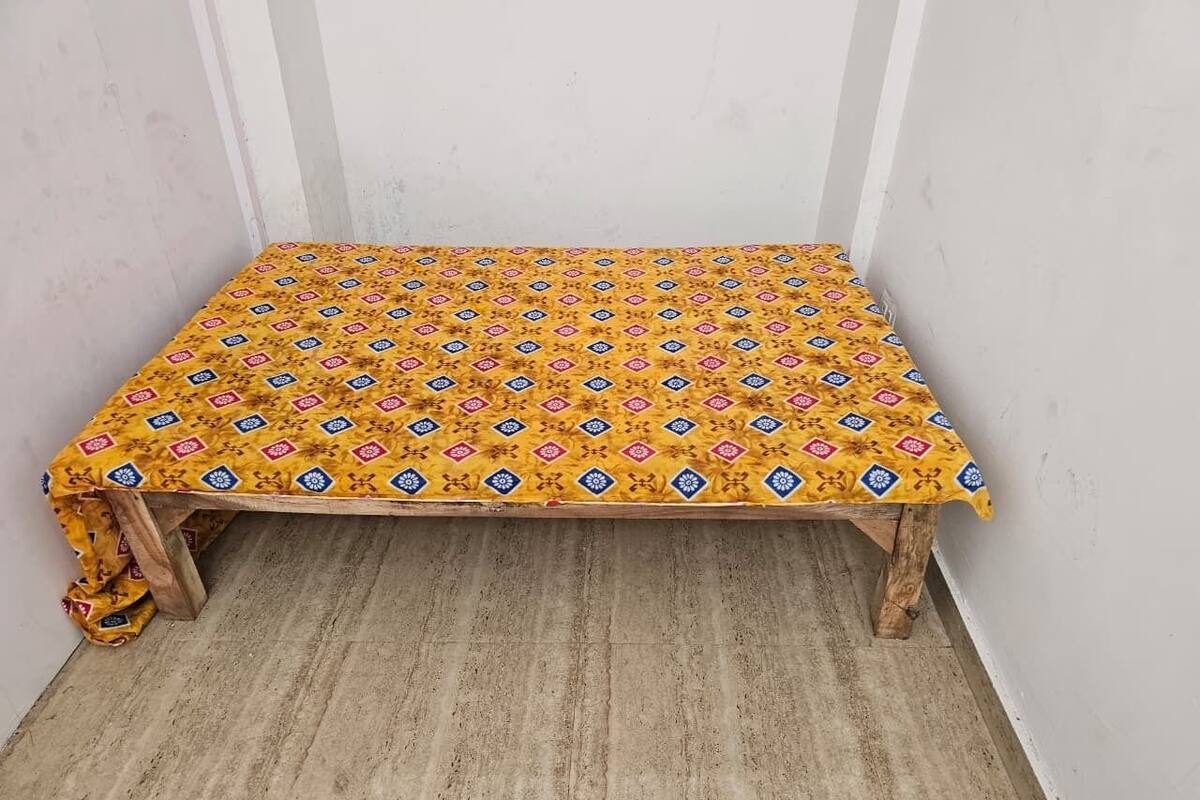 Um pequeno banco de madeira com toalha de mesa amarela estampada em um canto.