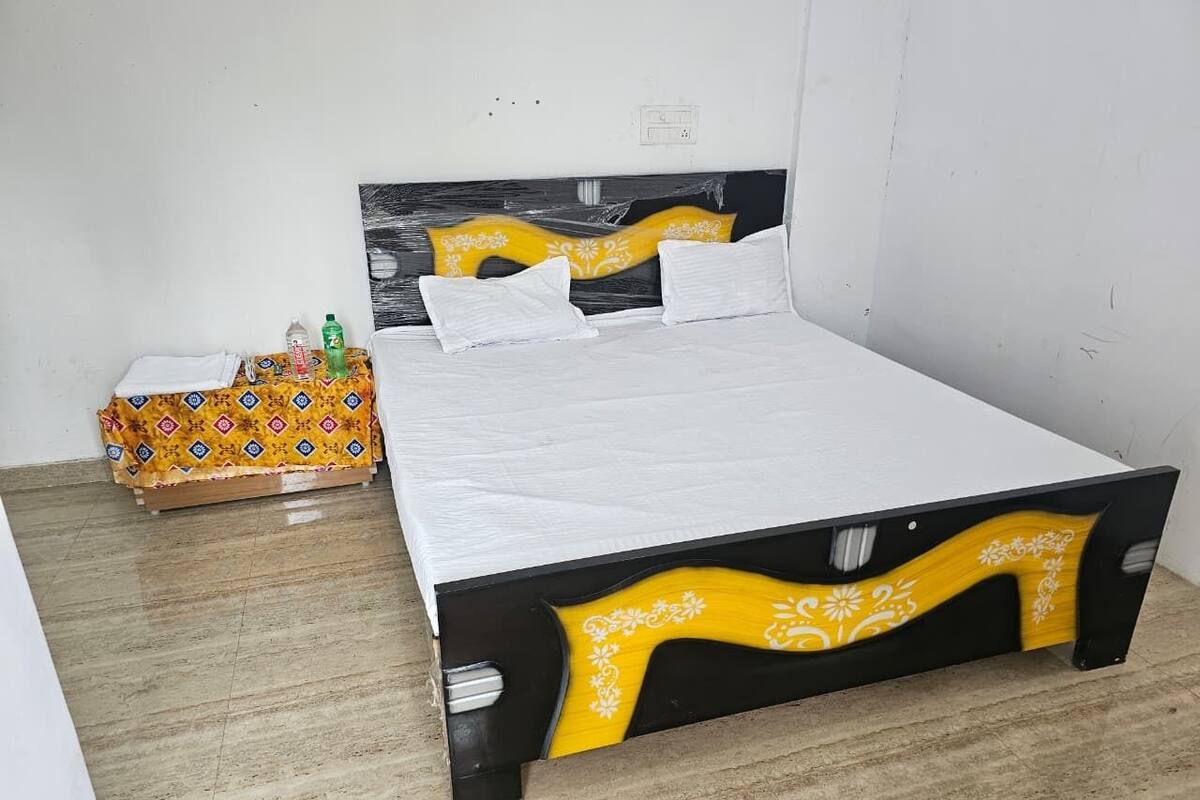 Uma cama com estrutura preta e amarela, roupa de cama branca e almofada estampada.